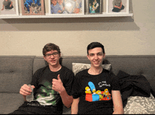 two boys are sitting on a couch with one wearing a simpsons t-shirt