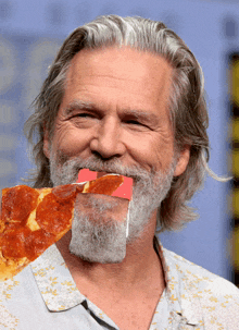 a man with a beard has a slice of pizza in his mouth