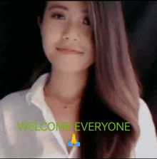 a woman in a white shirt is standing in front of the words welcome everyone