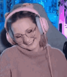 a woman wearing headphones and glasses is smiling in front of a computer screen .