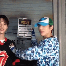 two young men are standing next to each other and one of them is holding a clipboard with a sign on it .