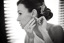 a woman adjusts her earrings in front of a mirror