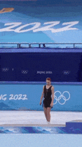 a woman in a black dress is standing on a podium in front of a sign that says beijing 2022 .