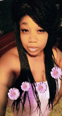 a woman with braids and purple flowers in her hair takes a selfie