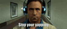 a man wearing headphones is standing in a hallway with the words `` stop your yapping '' .