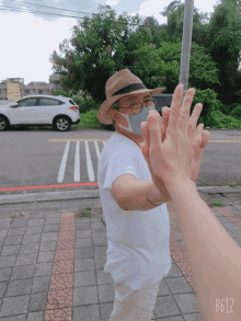 a man wearing a straw hat and a mask is giving a high five