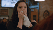 a woman wipes her nose with a napkin in a bar