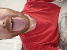 a man with a beard sticking his tongue out in a red shirt