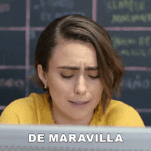 a woman is sitting in front of a computer with the words de maravilla written on the screen