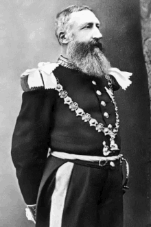 a black and white photo of a man with a beard wearing a black uniform