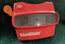 a red 3d view master is sitting on a green surface