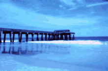 a pier in the ocean with a blue sky behind it