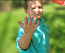 a young boy in a blue shirt waves his hand in the air