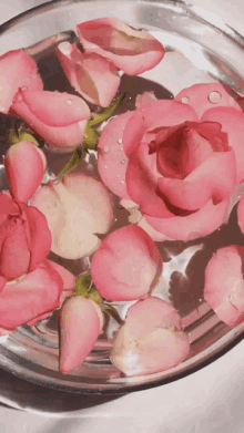 a glass bowl filled with pink roses and water drops