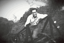 a black and white photo of a man standing on a railing