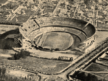 an aerial view of a stadium with a few cars parked around it