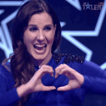 a woman in a blue dress making a heart shape with her hands in front of a sign that says got talent