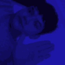 a man is laying down in a dark room with a blue background .