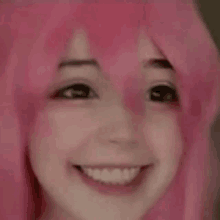 a close up of a person wearing a pink wig smiling .