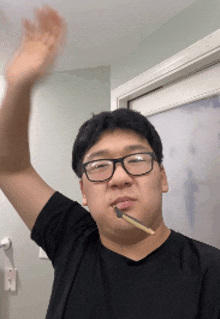 a man wearing glasses and a black shirt is brushing his teeth