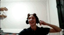 a young man wearing headphones is smiling in a bedroom