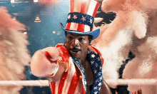 a man in an american flag outfit and top hat is pointing at the camera .