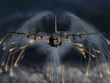 a large military plane is flying through the air with fireworks coming out of its wings .