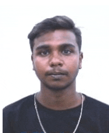 a young man wearing a black shirt and a gold chain is looking at the camera .