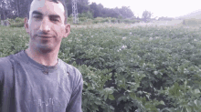 a man wearing a shirt that says ' a-star ' on it is standing in front of a field of potatoes