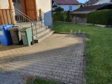 a brick walkway with a green trash can that says recycling