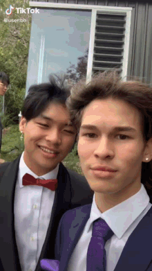 two young men are posing for a picture and one has a red bow tie and the other has a purple tie