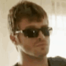 a close up of a man wearing sunglasses and a black shirt .