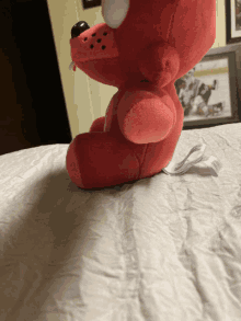 a red stuffed animal is sitting on a bed next to a picture of a hockey game