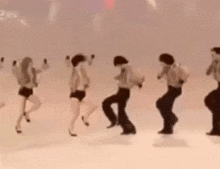 a group of people are dancing in front of a white wall with the number 2 on it