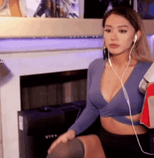 a woman in a blue crop top and black skirt is sitting in front of a fireplace .