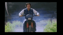 a man in a blue jacket is riding a motorcycle down a road