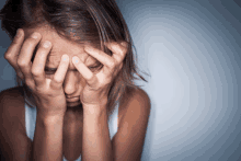 a woman is covering her face with her hands and looking down