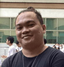 a man with a bun on his head is smiling in front of a building