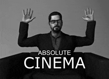 a man in a suit is sitting in a chair with his hands in the air and the words absolute cinema below him