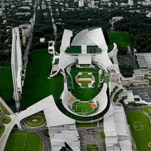 an aerial view of a large white stadium with a green field in front of it