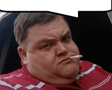 a fat man in a red shirt is smoking a cigarette while sitting in a car .