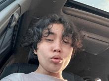 a young man with curly hair is sitting in the driver 's seat of a car