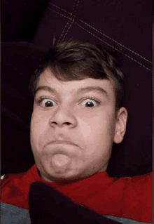 a young boy laying on a couch making a face