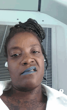 a woman with a tattoo on her neck has blue lipstick on