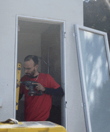 a man in a red shirt is working on a door