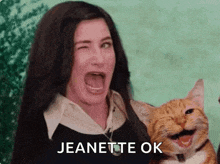 a woman is holding a cat and making a funny face while saying jeanette ok .