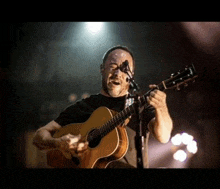 a man is singing into a microphone while holding a guitar