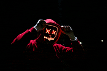 a person wearing a red hoodie with a light up mask that says xx