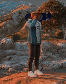 a man in a denim jacket is holding a skateboard with the letter t on it