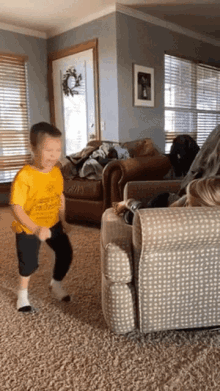 a young boy wearing a yellow shirt that says ' i love you ' on it is dancing in a living room